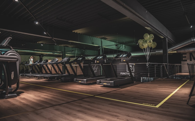 Classic gym floor with purple and yellow equipment, people working out.